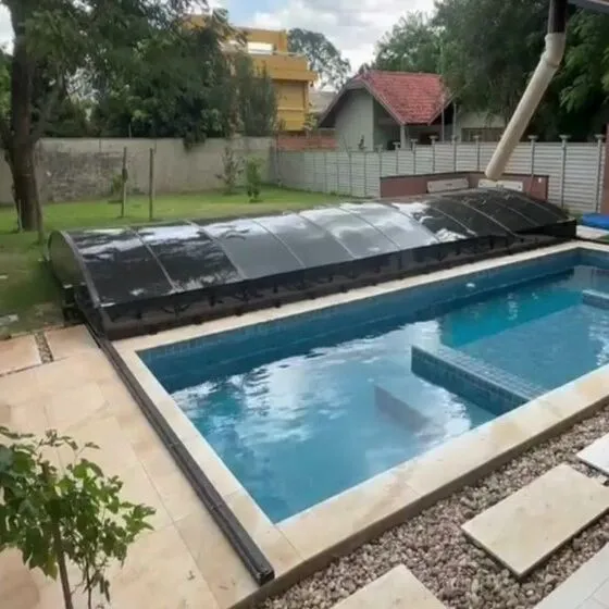 Piscina protegida por cobertura retrátil em dia chuvoso mantendo água limpa